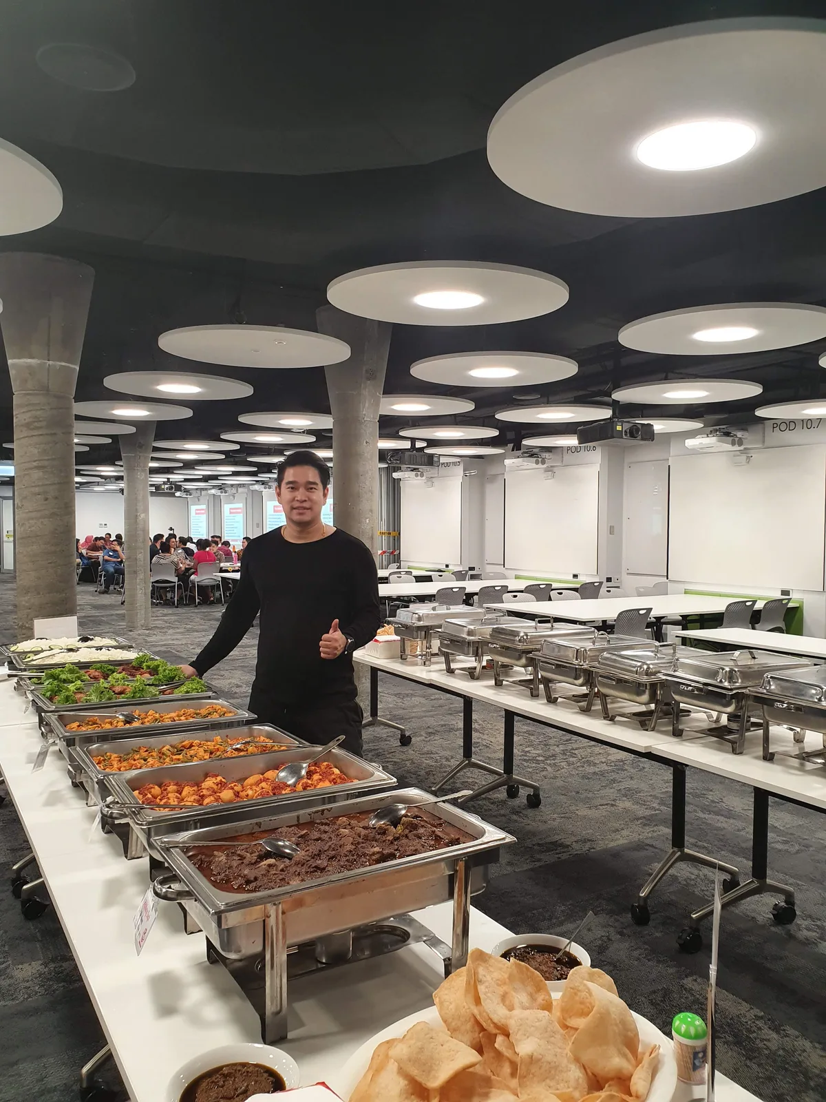 A member of the Makcel team beside a buffet of Indonesian dishes