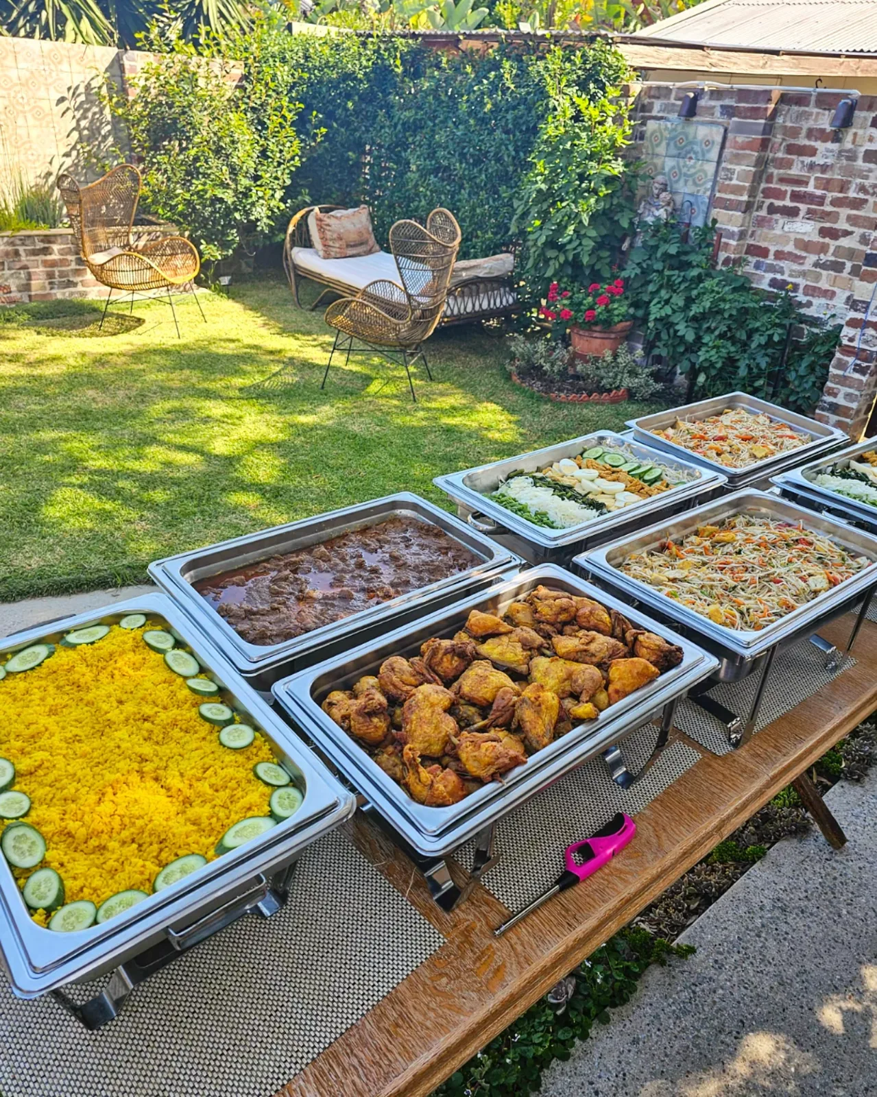 An outdoor buffet of yellow rice and Indonesian dishes